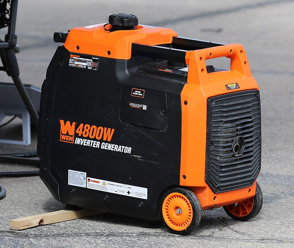 An orange and black WEN 4800 inverter generator with wheels, sitting on pavement, for storm prep in Iowa City, IA